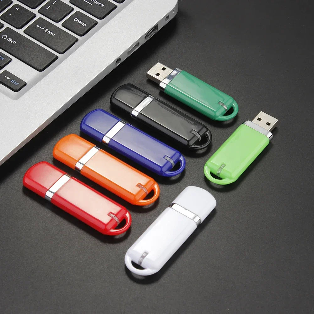 Assorted JASTER 64GB USB Flash Drives connected to a laptop, ideal for business gifts with USB 2.0 and sleek design.